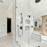 Shower with one wall made of glass, two walls of white ceramic, and one open wall.