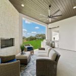 Open rest area with a fireplace, three couches, overseeing an open wall to the backyard filled with grass